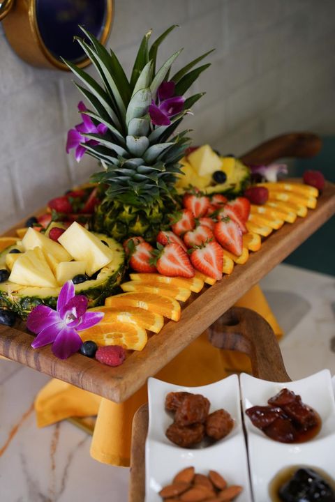 Fruit plate with pineapple, strawberries, oranges and berries, with dried fruit, almonds and preserves on the side